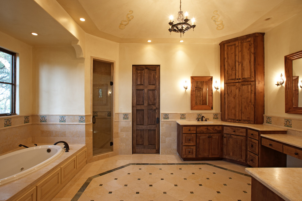 Mediterranean bathroom in Austin with raised-panel cabinets, dark wood cabinets, a drop-in tub, an alcove shower and beige tile.