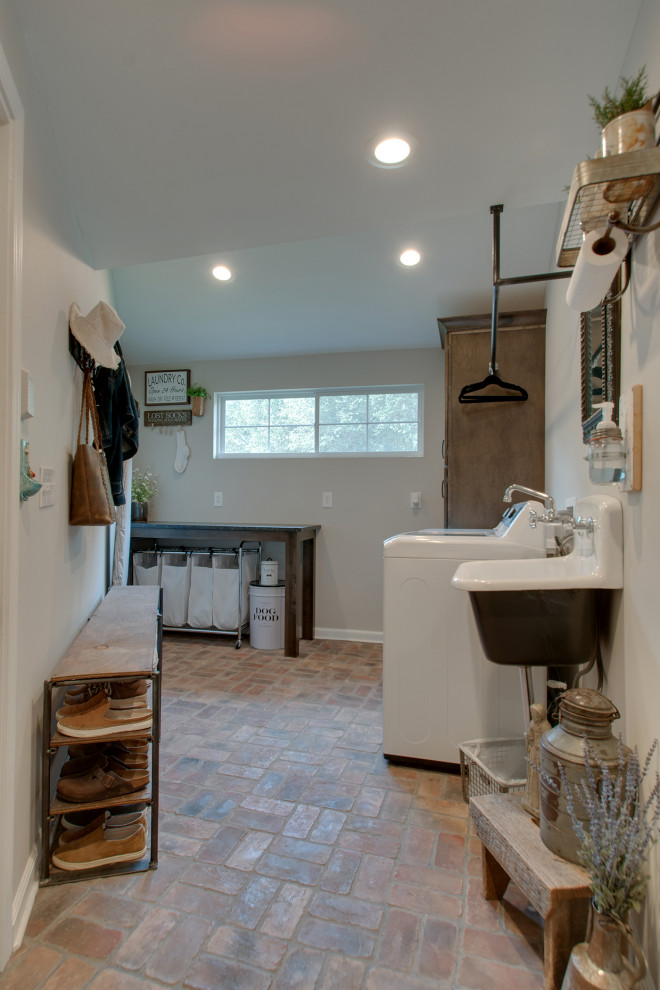 Inspiration for a small country utility room in Nashville with a farmhouse sink, shaker cabinets, brown cabinets, granite benchtops, grey walls, brick floors, a side-by-side washer and dryer, multi-coloured floor and black benchtop.