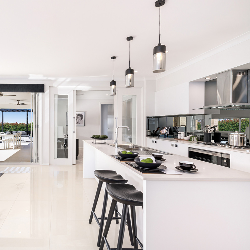 Large contemporary galley open plan kitchen in Other with a double-bowl sink, white cabinets, metallic splashback, mirror splashback, stainless steel appliances, ceramic floors, with island, white floor, flat-panel cabinets and turquoise benchtop.