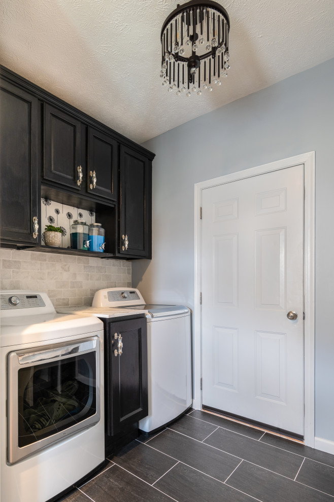 Small traditional galley utility room in Other with recessed-panel cabinets, black cabinets, engineered stone countertops, blue walls, ceramic flooring, a side by side washer and dryer and black floors.