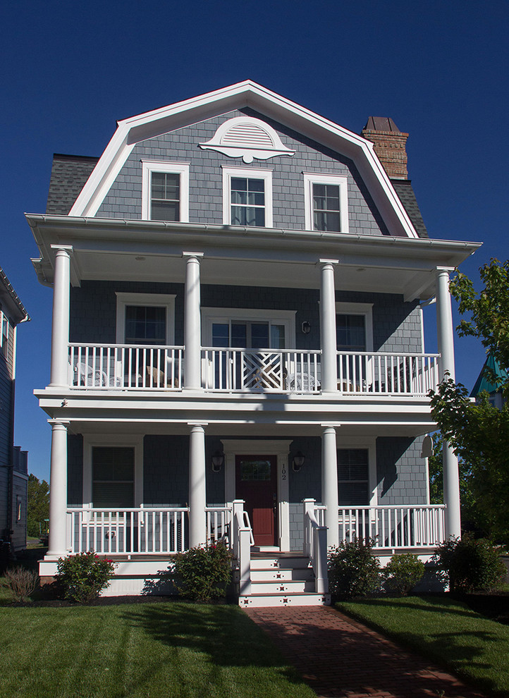 This is an example of a large traditional three-storey blue house exterior in Philadelphia with vinyl siding, a gambrel roof and a shingle roof.