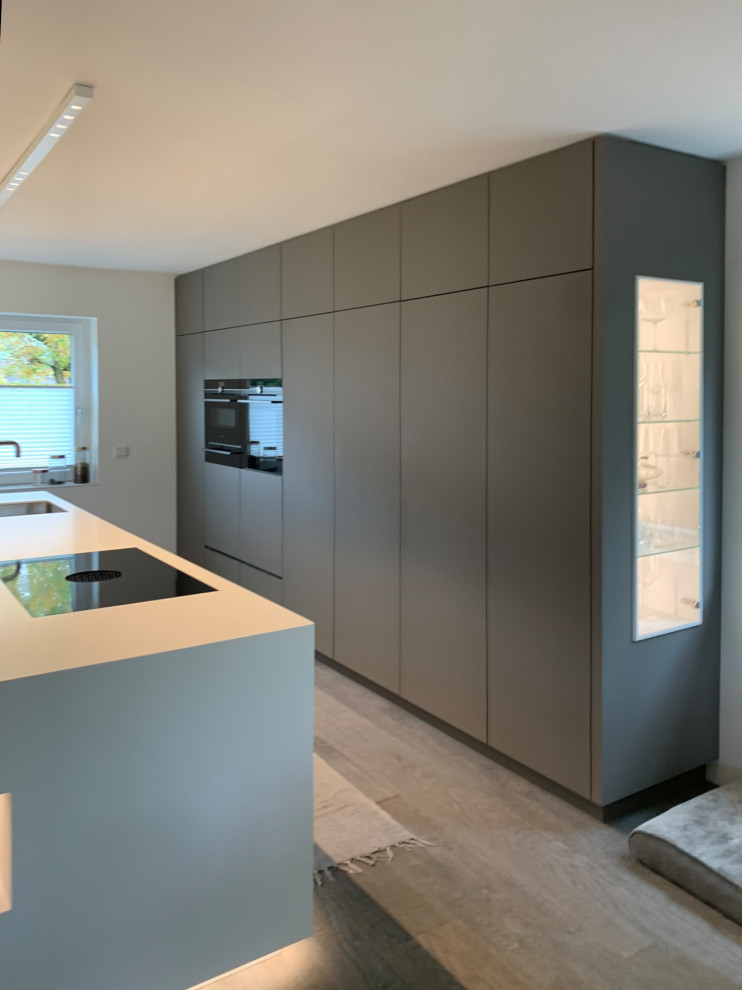 Aménagement d'une grande cuisine ouverte contemporaine avec des portes de placard grises, un plan de travail en surface solide, parquet peint et îlot.