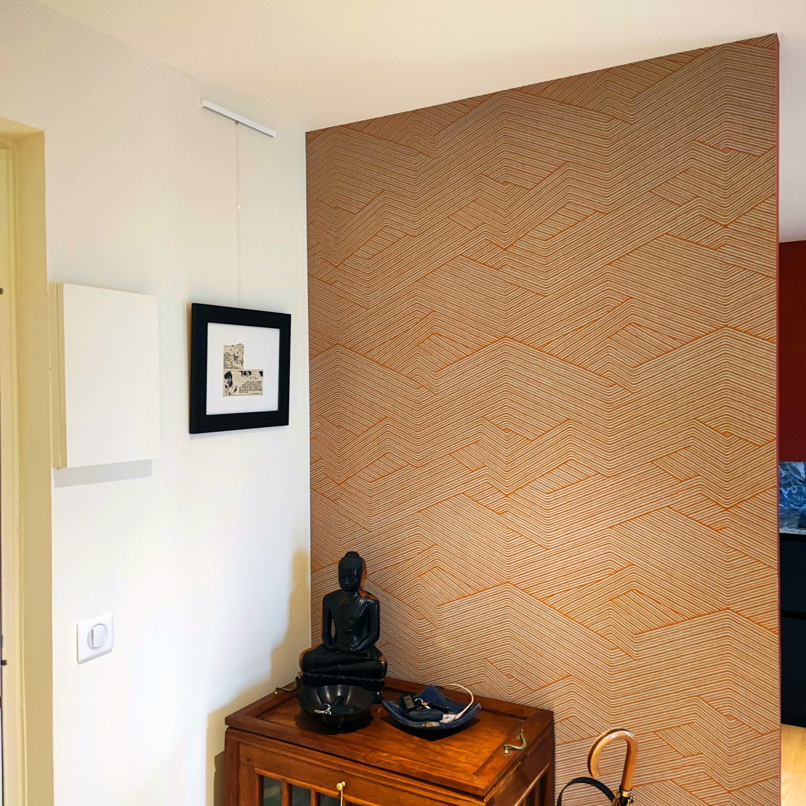 Un papier peint vous accueille dans l'entrée, et est in indice de la cuisine terracotta cachée derrière. Cette entrée est à la fois ouverte et intimiste. L'agencement sur mesure la cache des fenêtres,