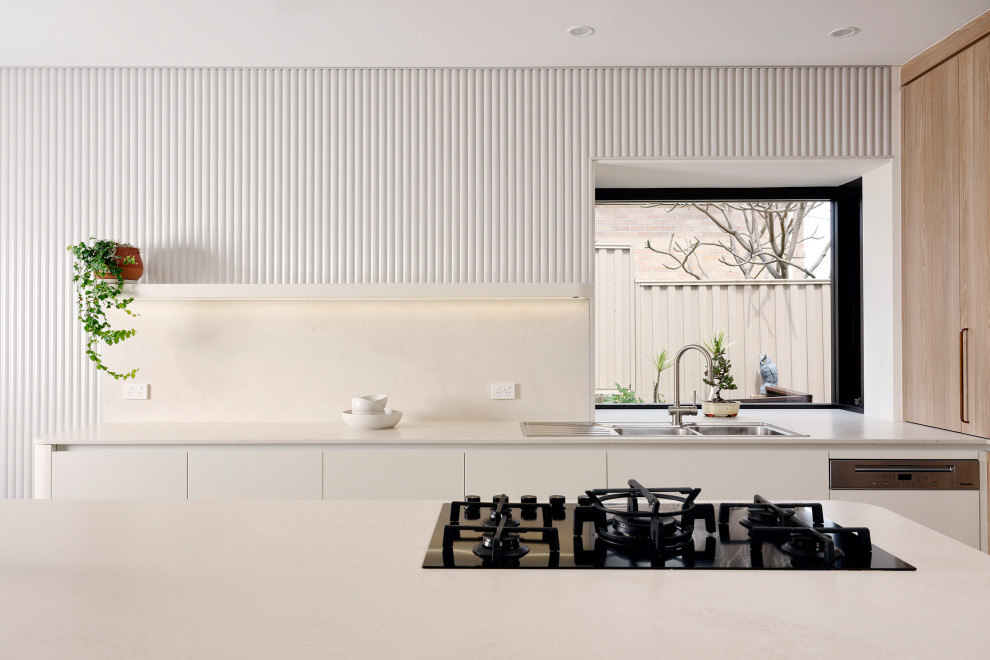 This is an example of a large scandinavian l-shaped eat-in kitchen in Perth with a double-bowl sink, flat-panel cabinets, white cabinets, quartz benchtops, white splashback, engineered quartz splashback, black appliances, slate floors, with island, black floor and white benchtop.