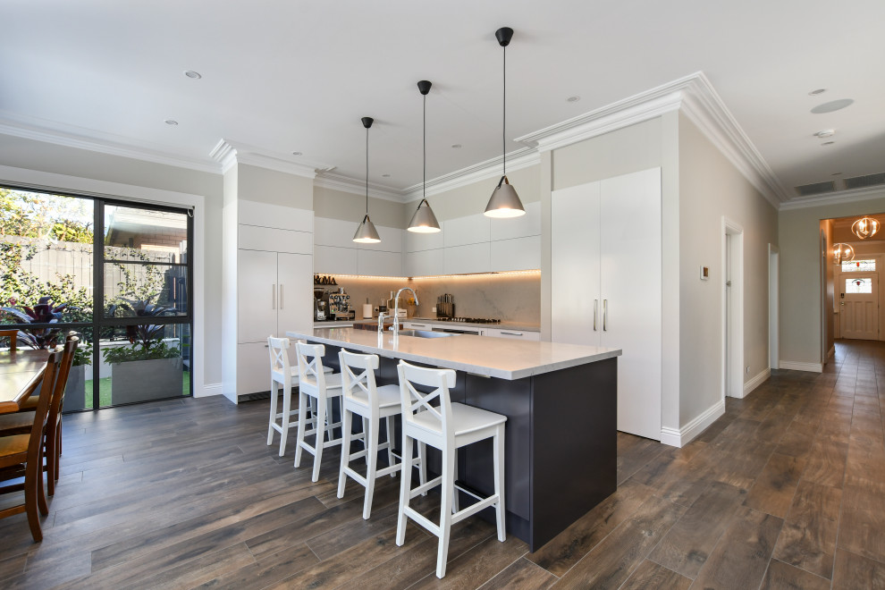 Inspiration for a mid-sized contemporary l-shaped eat-in kitchen in Sydney with a single-bowl sink, flat-panel cabinets, white cabinets, grey splashback, panelled appliances, medium hardwood floors, with island, brown floor and grey benchtop.