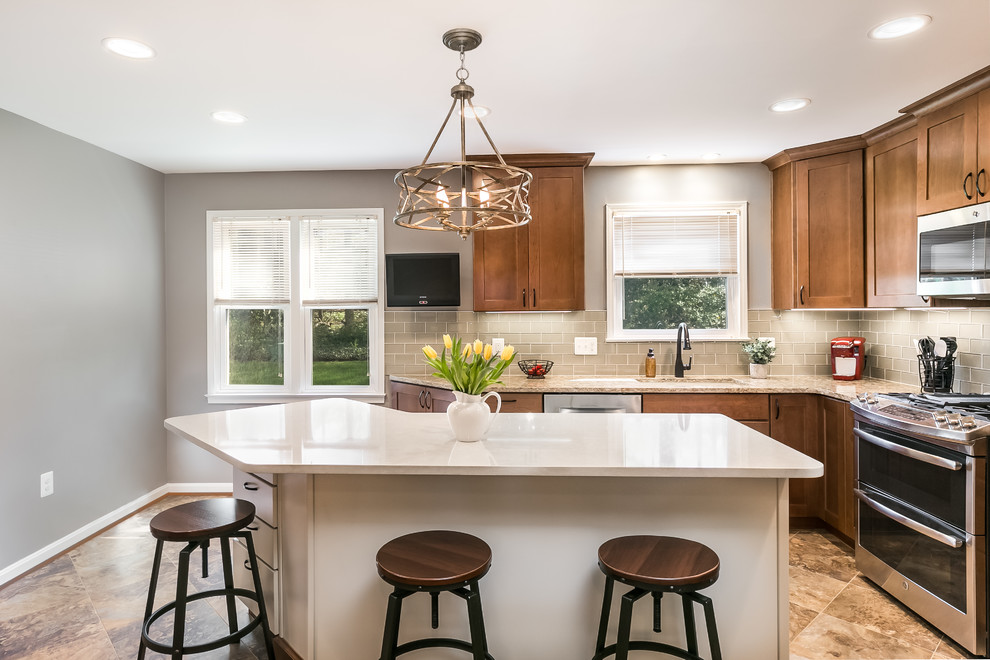 Mid-sized transitional l-shaped separate kitchen in DC Metro with an undermount sink, shaker cabinets, medium wood cabinets, quartz benchtops, grey splashback, glass tile splashback, stainless steel appliances, vinyl floors, with island and brown floor.