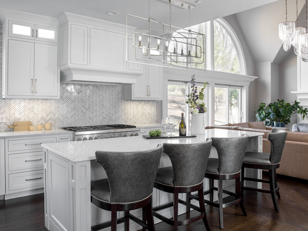 Inspiration for a mid-sized transitional l-shaped open plan kitchen in Chicago with shaker cabinets, white cabinets, stainless steel appliances, dark hardwood floors, brown floor, white benchtop, marble benchtops, white splashback, mosaic tile splashback, a farmhouse sink and multiple islands.