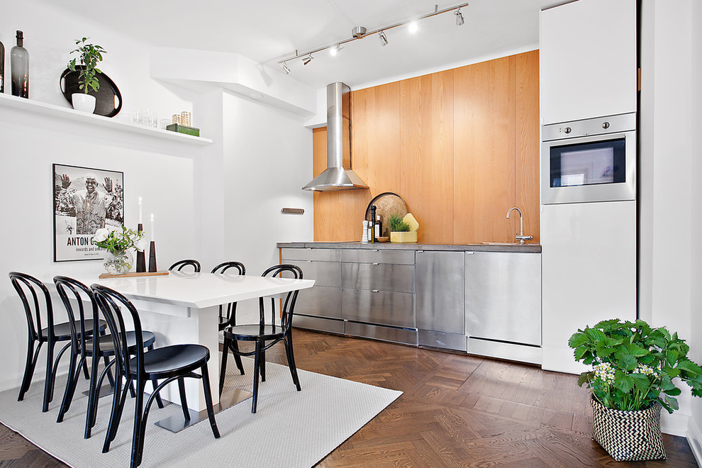 Photo of a mid-sized scandinavian single-wall kitchen in Stockholm with flat-panel cabinets, stainless steel cabinets, concrete benchtops, stainless steel appliances, dark hardwood floors and no island.
