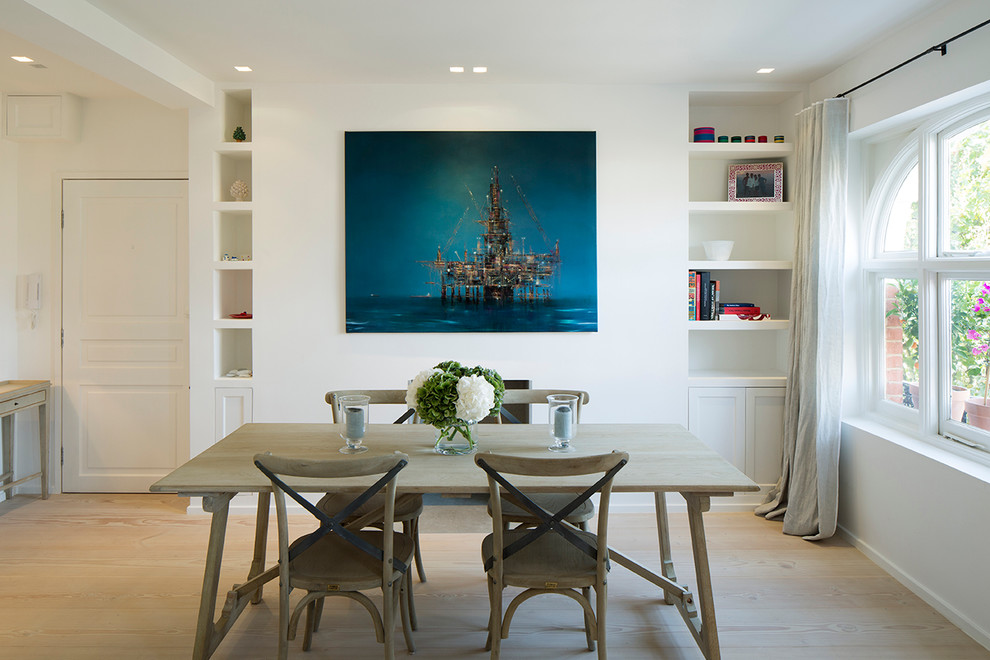 Photo of a large contemporary dining room in London with white walls, light hardwood floors and a standard fireplace.