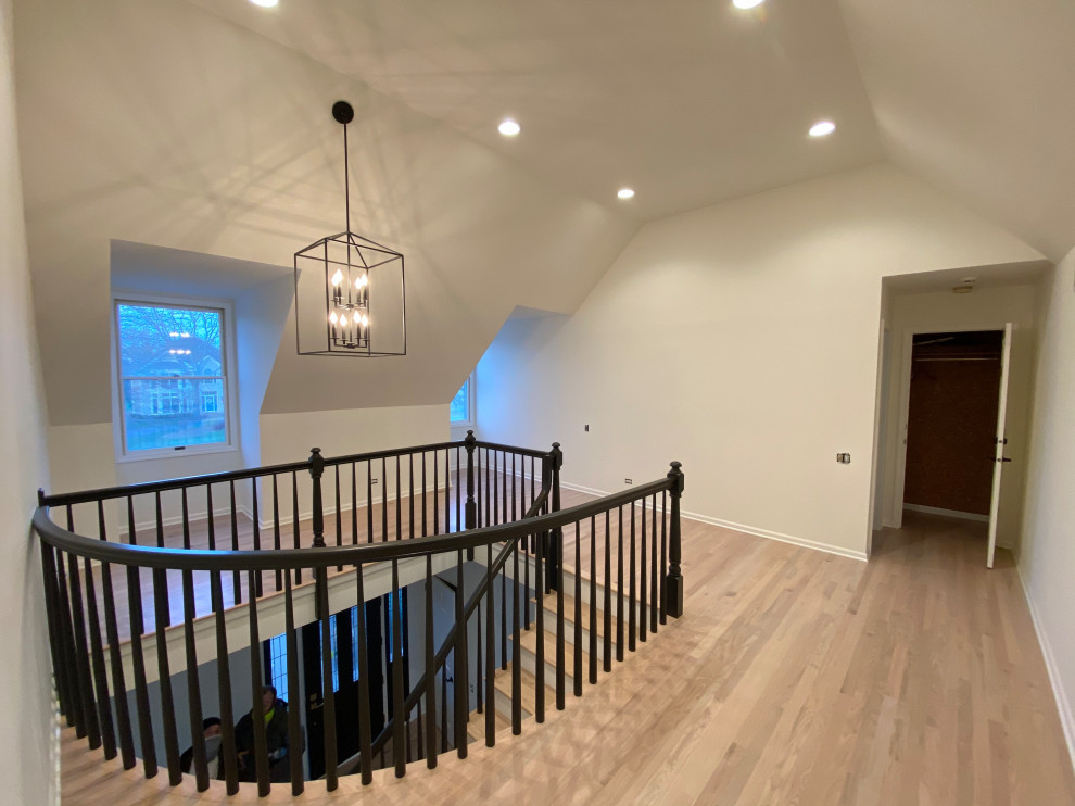 Large minimalist wooden curved wood railing and wood wall staircase photo in Chicago with painted risers