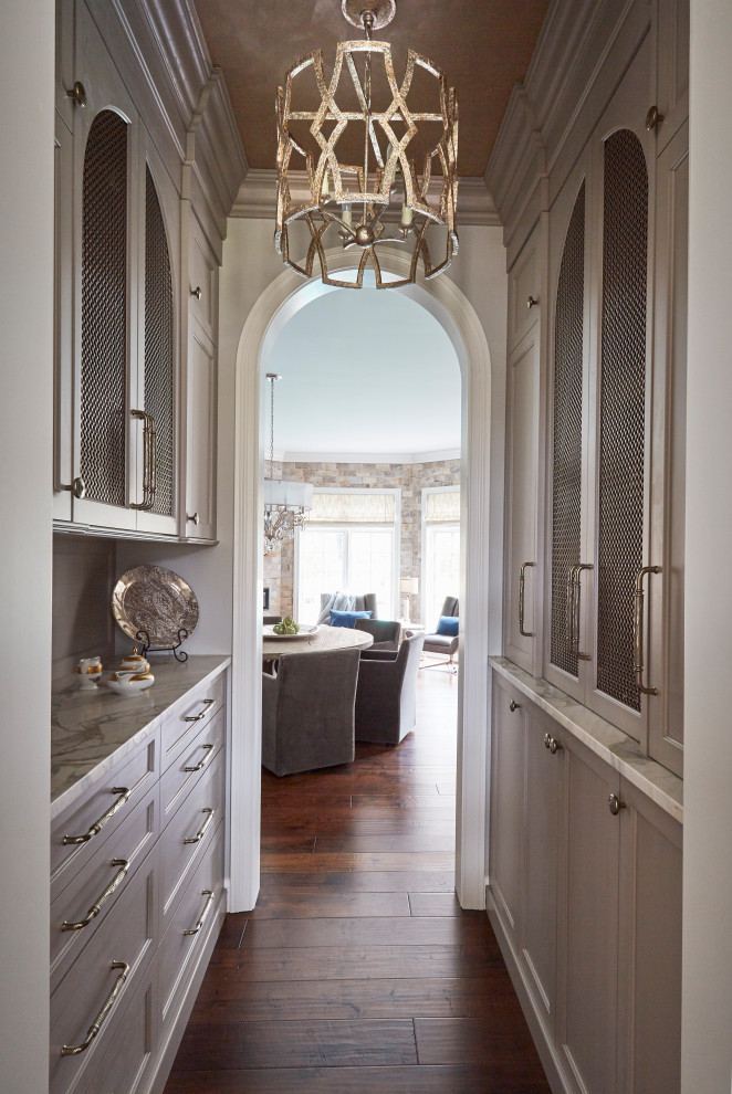 This is an example of an expansive traditional u-shaped kitchen pantry in Chicago with an undermount sink, recessed-panel cabinets, white cabinets, marble benchtops, white splashback, marble splashback, panelled appliances, dark hardwood floors, with island, brown floor and white benchtop.
