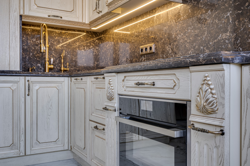 This is an example of a large traditional l-shaped kitchen/diner in Moscow with beaded cabinets, beige cabinets, engineered stone countertops, black splashback, engineered quartz splashback, black appliances, ceramic flooring, no island, white floors, black worktops and a feature wall.