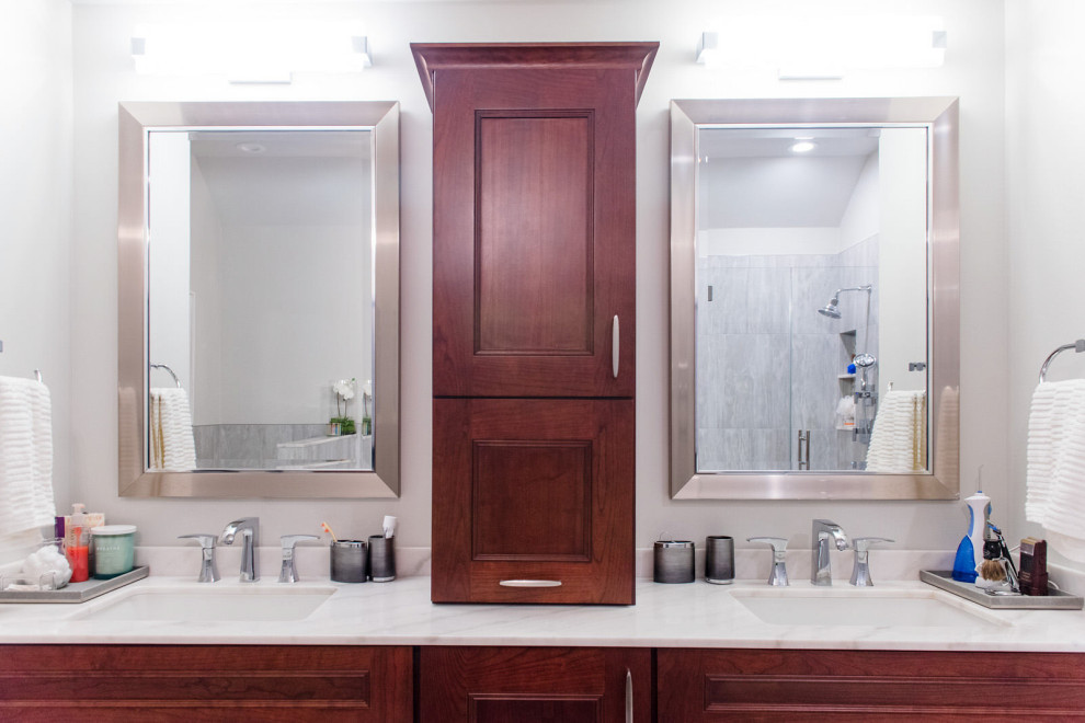 Photo of a large contemporary master bathroom in New York with recessed-panel cabinets, dark wood cabinets, a corner shower, porcelain tile, porcelain floors, an undermount sink, marble benchtops, grey floor, a hinged shower door, white benchtops, a shower seat, a double vanity, a built-in vanity and vaulted.