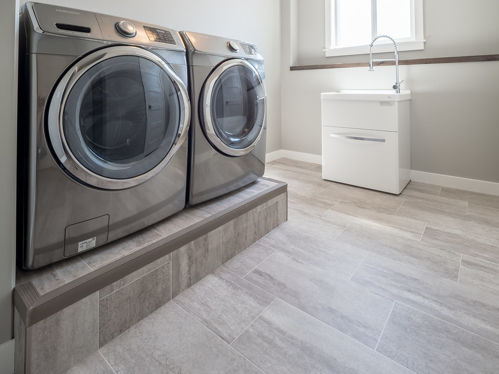 Mid-sized traditional single-wall dedicated laundry room in Edmonton with an integrated sink, grey walls, vinyl floors, a side-by-side washer and dryer and grey floor.