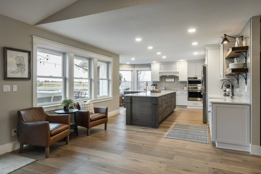 Large cottage l-shaped medium tone wood floor and brown floor open concept kitchen photo in Boise with a farmhouse sink, shaker cabinets, white cabinets, quartz countertops, gray backsplash, porcelain backsplash, stainless steel appliances, an island and white countertops
