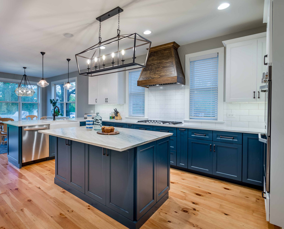 Modelo de cocina blanca y madera de estilo de casa de campo grande con fregadero sobremueble, armarios estilo shaker, puertas de armario turquesas, encimera de mármol, salpicadero blanco, salpicadero de azulejos de porcelana, electrodomésticos de acero inoxidable, suelo de madera clara, una isla, suelo marrón y encimeras multicolor