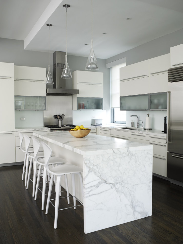 Contemporary l-shaped kitchen in New York with stainless steel appliances, white cabinets, marble benchtops and flat-panel cabinets.