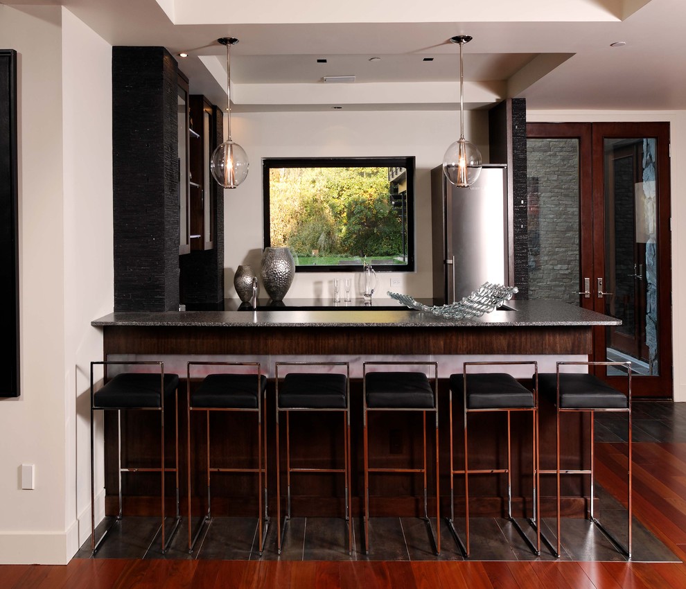 This is an example of a large contemporary u-shaped seated home bar in DC Metro with dark hardwood floors, dark wood cabinets, granite benchtops and brown floor.