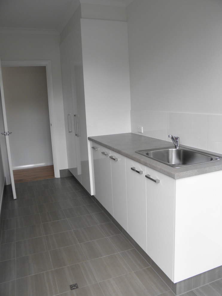 Design ideas for a contemporary laundry room in Perth with a single-bowl sink, laminate benchtops, white walls and ceramic floors.