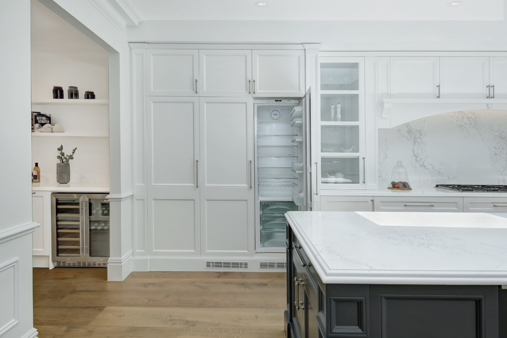 Example of a large trendy galley light wood floor and brown floor kitchen pantry design in Sydney with a farmhouse sink, shaker cabinets, white cabinets, quartz countertops, white backsplash, quartz backsplash, stainless steel appliances, an island and white countertops