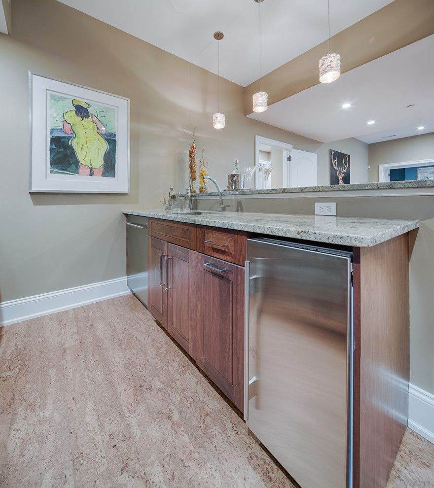 Photo of a traditional galley wet bar in Philadelphia with an undermount sink, recessed-panel cabinets, medium wood cabinets, marble benchtops, grey splashback and cork floors.