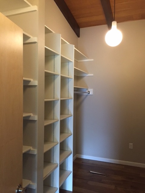 This is an example of a mid-sized midcentury gender-neutral walk-in wardrobe in Cedar Rapids with white cabinets, open cabinets and dark hardwood floors.
