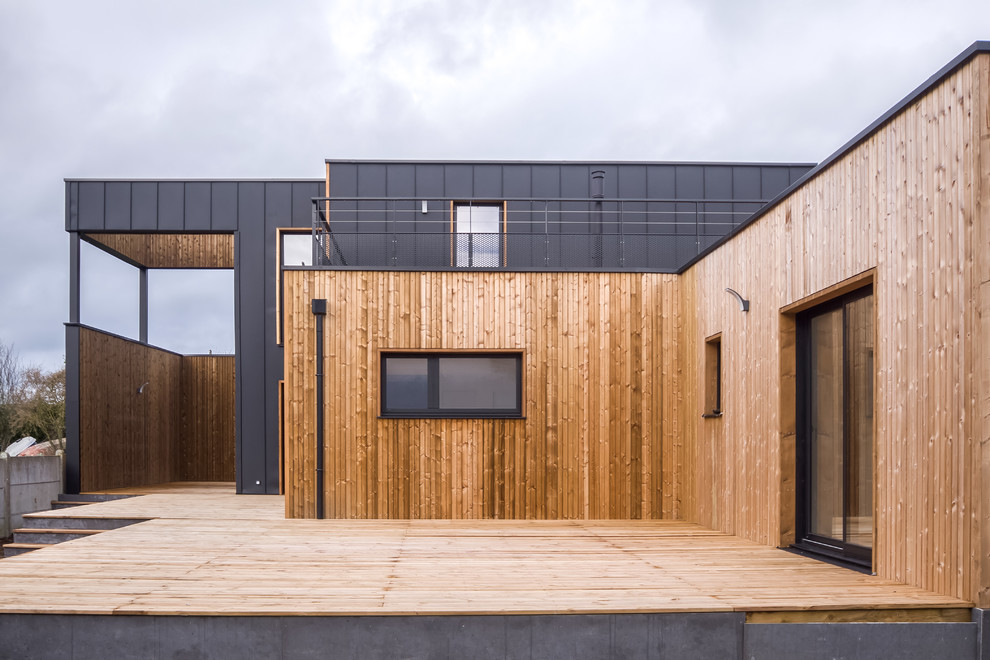 Photo of a large beach style two-storey black house exterior in Rennes with metal siding, a flat roof and a mixed roof.