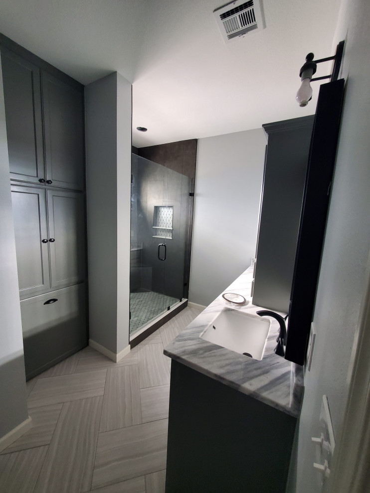 Foto på ett mellanstort funkis flerfärgad en-suite badrum, med luckor med profilerade fronter, vita skåp, en hörndusch, en toalettstol med separat cisternkåpa, grå kakel, grå väggar, cementgolv, ett nedsänkt handfat, bänkskiva i kvarts, grått golv och dusch med gångjärnsdörr