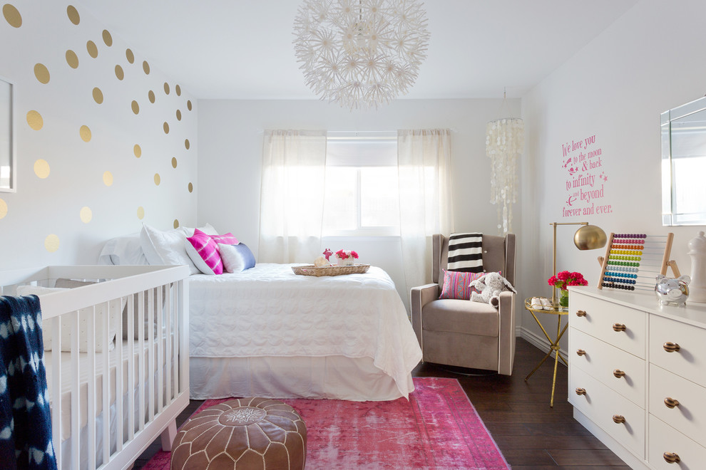 Small eclectic nursery in Los Angeles with white walls, laminate floors and brown floor for girls.