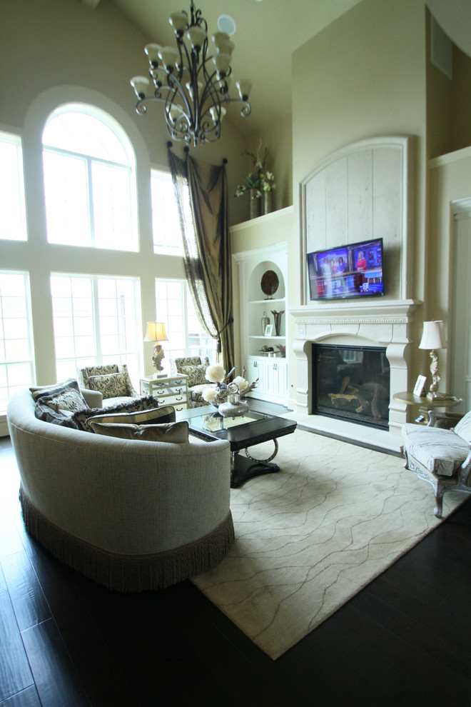 This is an example of a large traditional open concept family room in Houston with beige walls, dark hardwood floors, a standard fireplace, a concrete fireplace surround, a wall-mounted tv and brown floor.