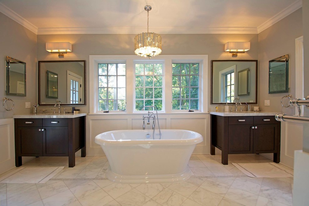 Mid-sized transitional master bathroom in New York with shaker cabinets, dark wood cabinets, a freestanding tub, grey walls, an undermount sink, beige floor and marble floors.