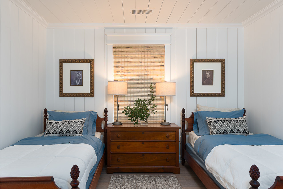 Photo of a mid-sized country guest bedroom in Other with white walls, medium hardwood floors, no fireplace and brown floor.