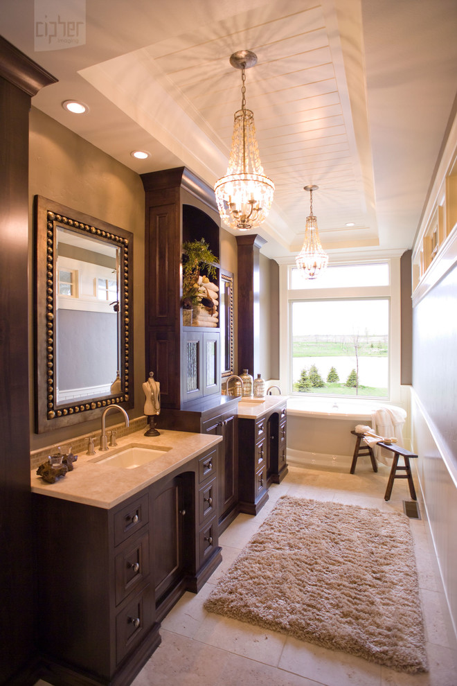 Mountain style master freestanding bathtub photo with an undermount sink, recessed-panel cabinets, dark wood cabinets and beige walls