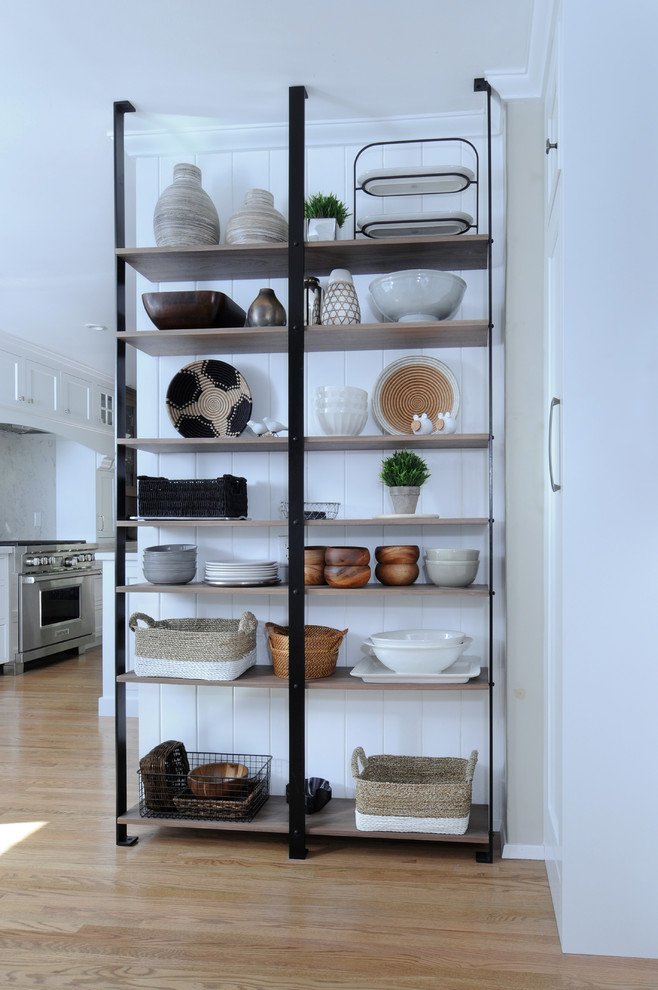 This is an example of a large transitional u-shaped kitchen pantry in Los Angeles with a farmhouse sink, recessed-panel cabinets, white cabinets, quartzite benchtops, white splashback, stone slab splashback, stainless steel appliances, light hardwood floors, with island, beige floor and white benchtop.