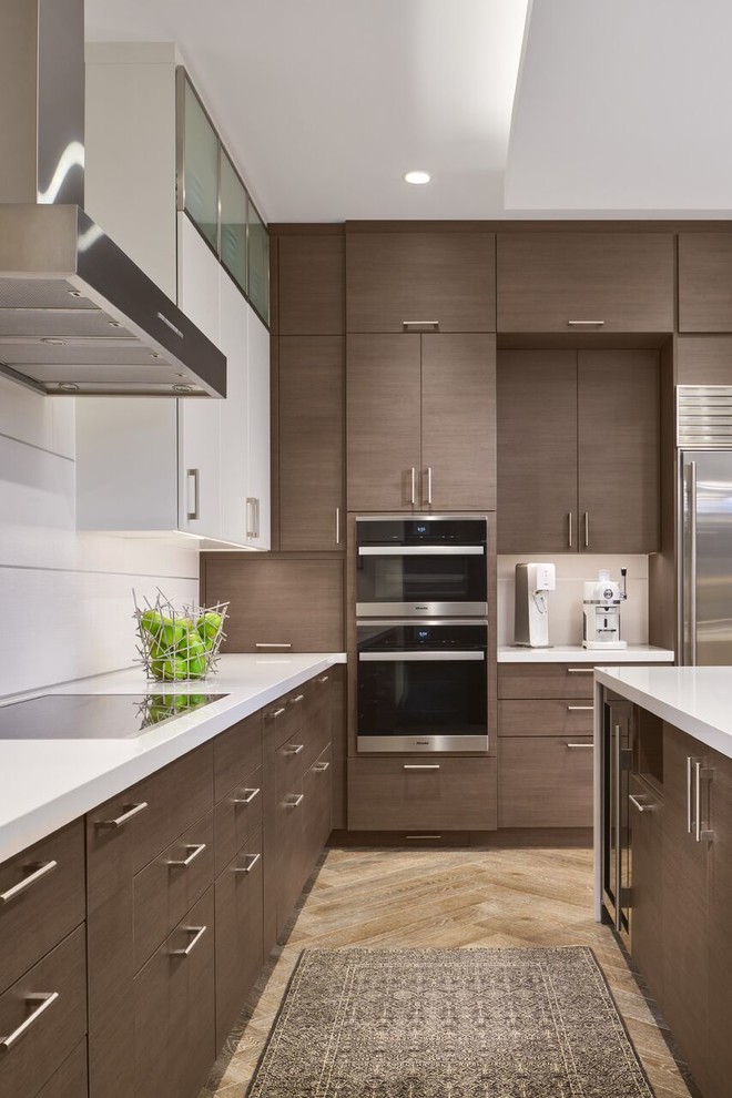 Design ideas for a large contemporary l-shaped eat-in kitchen in Chicago with an undermount sink, flat-panel cabinets, brown cabinets, solid surface benchtops, stainless steel appliances, light hardwood floors, with island and brown floor.