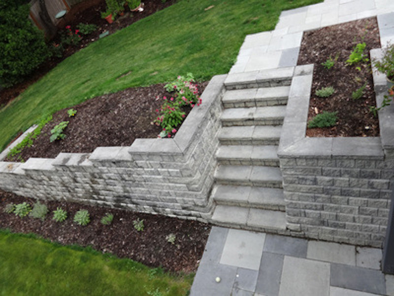 This is an example of a mid-sized traditional front yard full sun formal garden for summer in Seattle with a retaining wall and natural stone pavers.