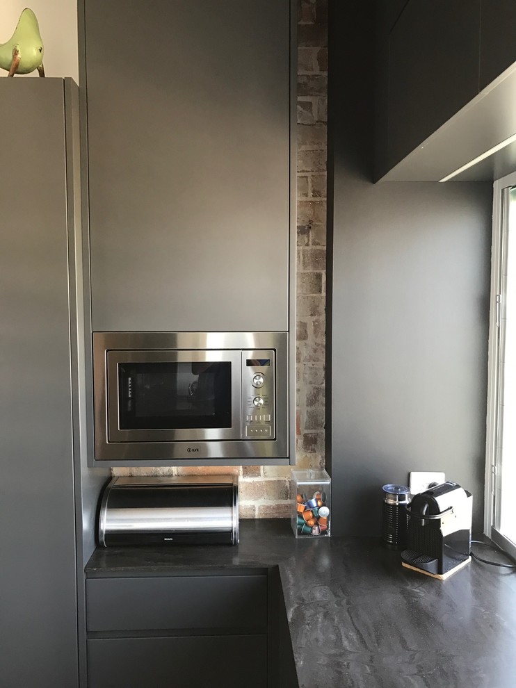 Mid-sized industrial u-shaped separate kitchen in Newcastle - Maitland with an undermount sink, marble benchtops, glass sheet splashback, stainless steel appliances, concrete floors and with island.