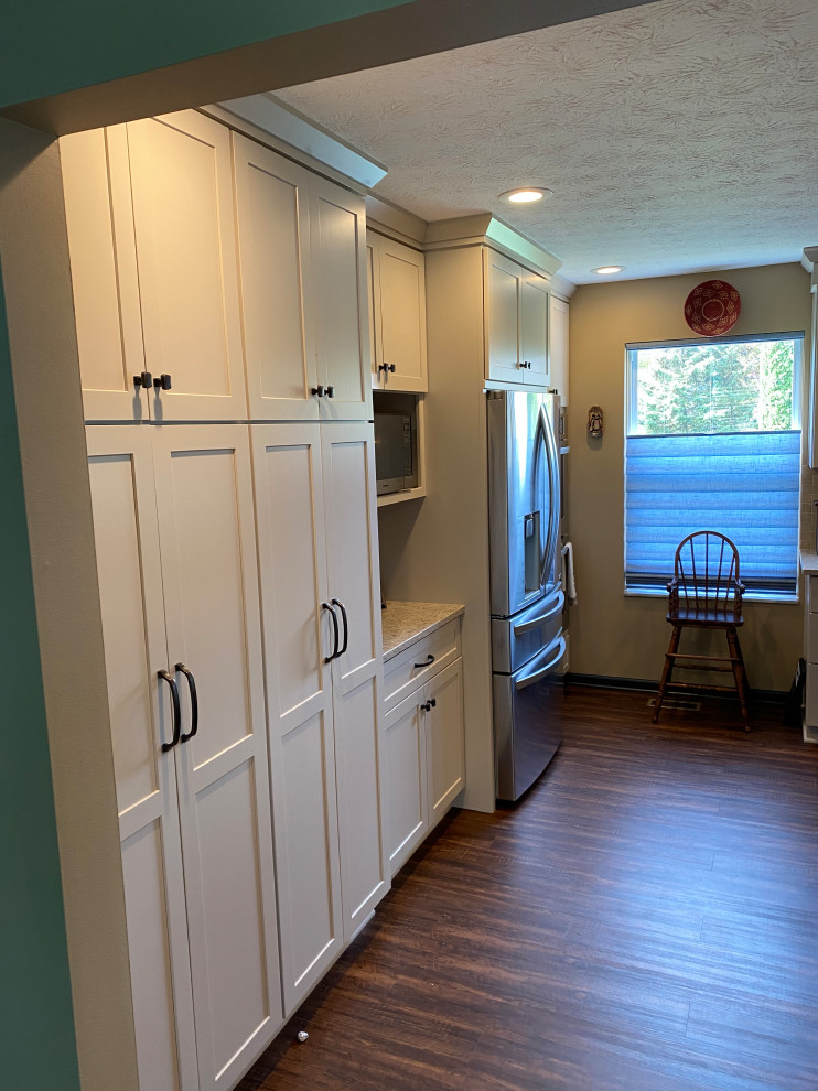 Foto på ett stort funkis brun kök, med en enkel diskho, luckor med infälld panel, vita skåp, träbänkskiva, beige stänkskydd, stänkskydd i marmor, rostfria vitvaror, vinylgolv, en köksö och brunt golv