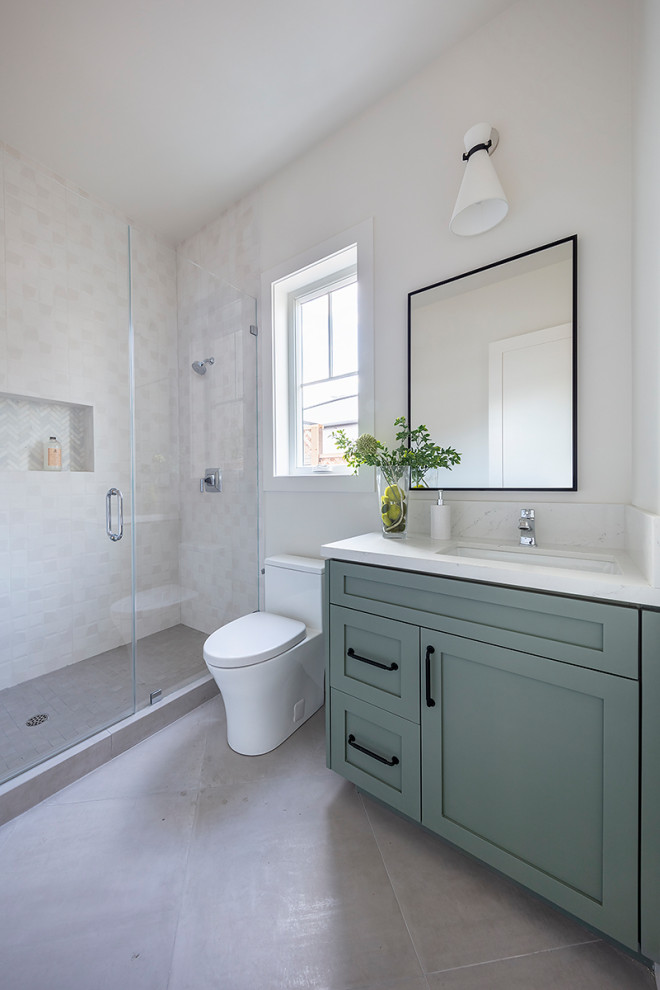 Пример оригинального дизайна: ванная комната среднего размера в стиле кантри с фасадами в стиле шейкер, зелеными фасадами, душем в нише, унитазом-моноблоком, белой плиткой, керамической плиткой, белыми стенами, полом из керамогранита, душевой кабиной, врезной раковиной, столешницей из искусственного кварца, белым полом, душем с распашными дверями, белой столешницей, нишей, тумбой под одну раковину и встроенной тумбой