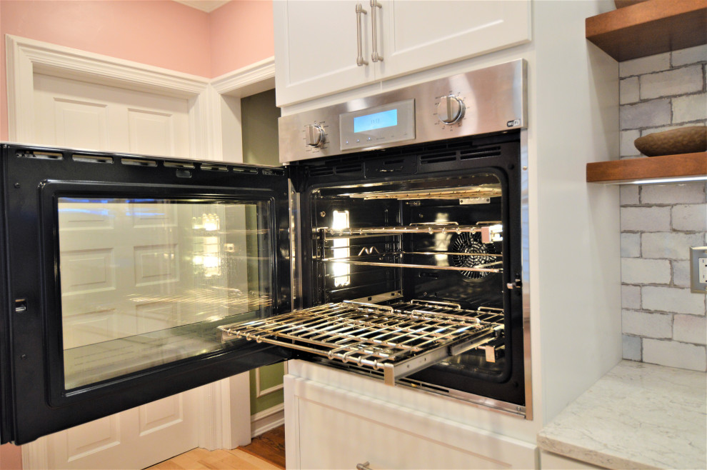 Small transitional light wood floor kitchen photo in Milwaukee with a single-bowl sink, shaker cabinets, white cabinets, quartzite countertops, ceramic backsplash and stainless steel appliances