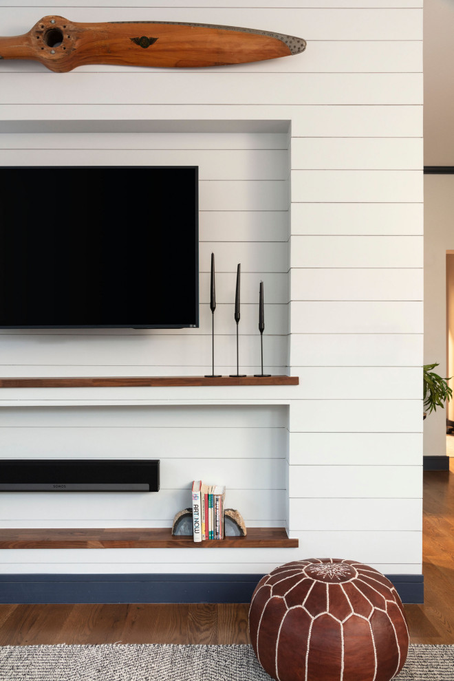Inredning av ett klassiskt mellanstort separat vardagsrum, med vita väggar, mellanmörkt trägolv, en väggmonterad TV och brunt golv
