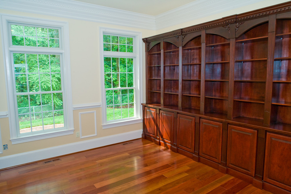 Photo of an expansive traditional home office in DC Metro with yellow walls, dark hardwood floors and no fireplace.