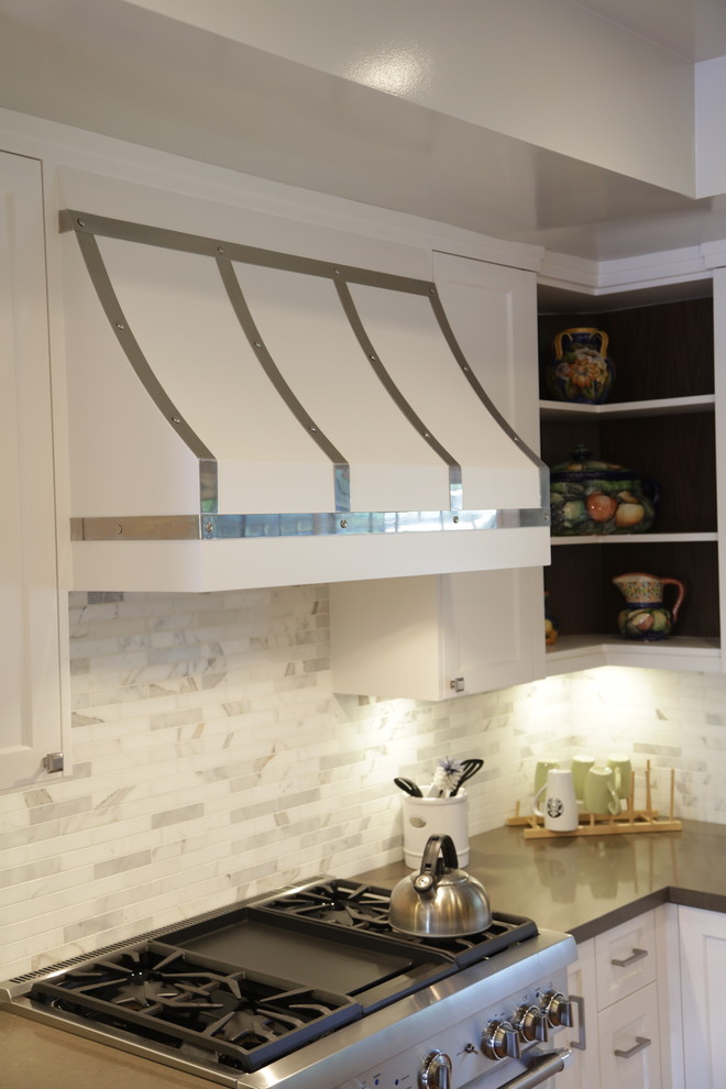 Example of a large transitional u-shaped medium tone wood floor eat-in kitchen design in Los Angeles with an undermount sink, recessed-panel cabinets, white cabinets, wood countertops, white backsplash, stone tile backsplash, stainless steel appliances and an island