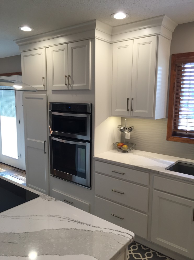 Large transitional l-shaped dark wood floor eat-in kitchen photo with an undermount sink, flat-panel cabinets, white cabinets, quartz countertops, white backsplash, ceramic backsplash, stainless steel appliances and an island