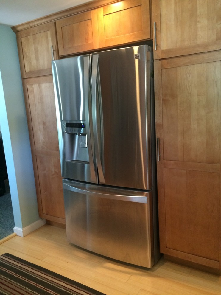 Inspiration for a transitional galley light wood floor eat-in kitchen remodel in Boston with an undermount sink, shaker cabinets, medium tone wood cabinets, quartz countertops, stainless steel appliances, no island and white countertops