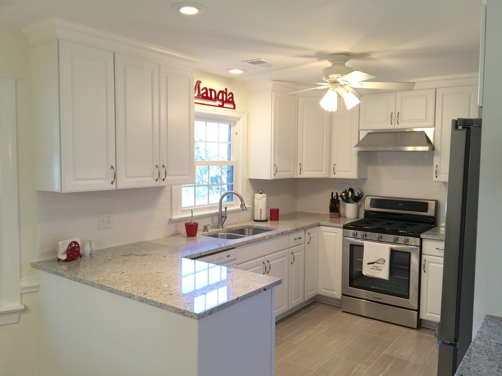 Example of a mid-sized transitional u-shaped porcelain tile enclosed kitchen design with an undermount sink, raised-panel cabinets, white cabinets, granite countertops, white backsplash, ceramic backsplash, stainless steel appliances and a peninsula