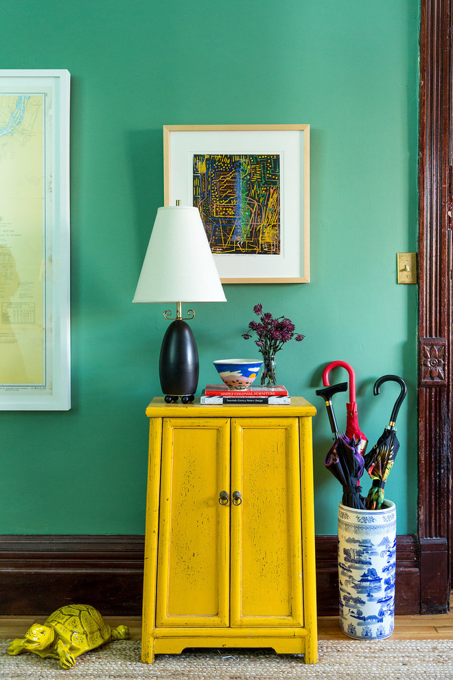 This is an example of an eclectic entryway in New York with green walls and light hardwood floors.