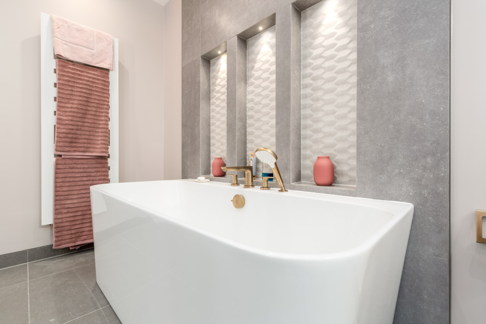 Стильный дизайн: детская ванная комната среднего размера в стиле модернизм с плоскими фасадами, коричневыми фасадами, отдельно стоящей ванной, душевой комнатой, инсталляцией, серой плиткой, керамической плиткой, розовыми стенами, полом из керамогранита, подвесной раковиной, столешницей из искусственного камня, серым полом, душем с распашными дверями, белой столешницей, нишей, тумбой под две раковины, подвесной тумбой и многоуровневым потолком - последний тренд