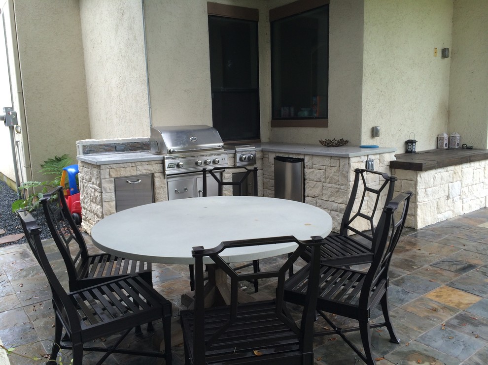 Contemporary side yard patio in Houston with an outdoor kitchen, natural stone pavers and a pergola.