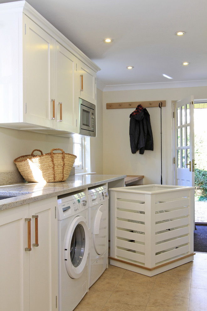 Design ideas for a traditional laundry room in Hampshire with white cabinets.